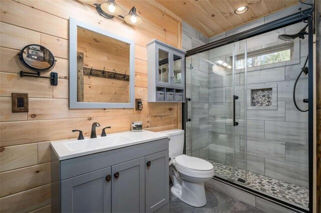 bathroom with vanity, wooden walls, a shower with shower door, and toilet