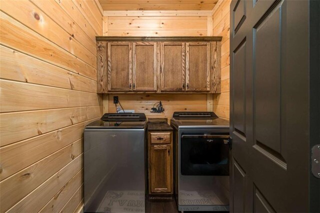 laundry area with cabinets, wooden walls, and washing machine and dryer