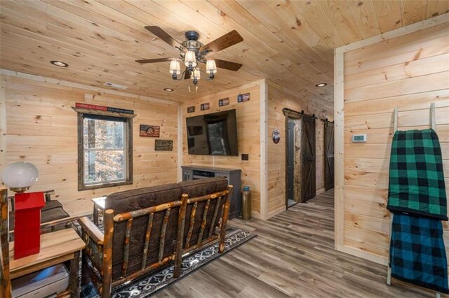 interior space featuring wood-type flooring, a barn door, wood ceiling, and wood walls