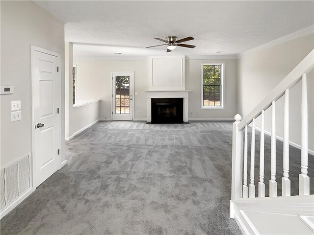 unfurnished living room with ceiling fan, ornamental molding, and carpet