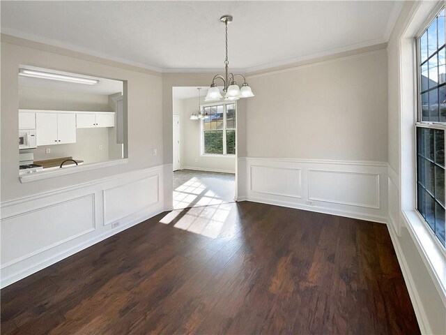 unfurnished dining area with ornamental molding, a notable chandelier, and dark hardwood / wood-style floors