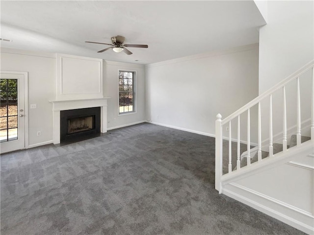 unfurnished living room featuring ornamental molding, ceiling fan, and dark carpet