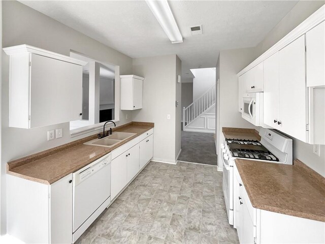 kitchen with white appliances, white cabinetry, and sink