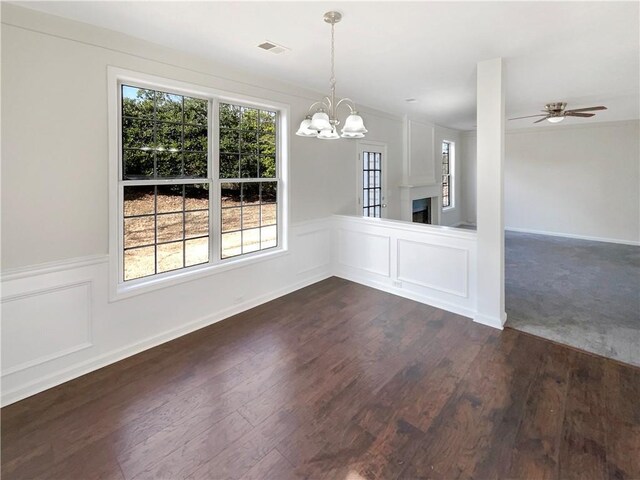 unfurnished dining area featuring ceiling fan with notable chandelier and dark hardwood / wood-style flooring