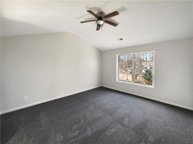 empty room featuring lofted ceiling, ceiling fan, and dark colored carpet