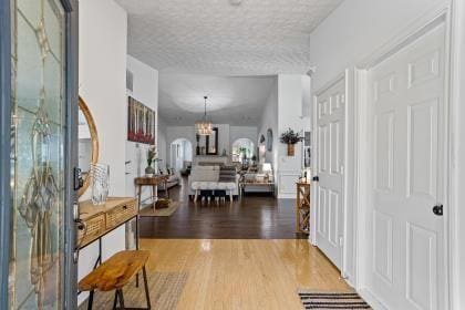 foyer featuring wood-type flooring, a textured ceiling, and a notable chandelier