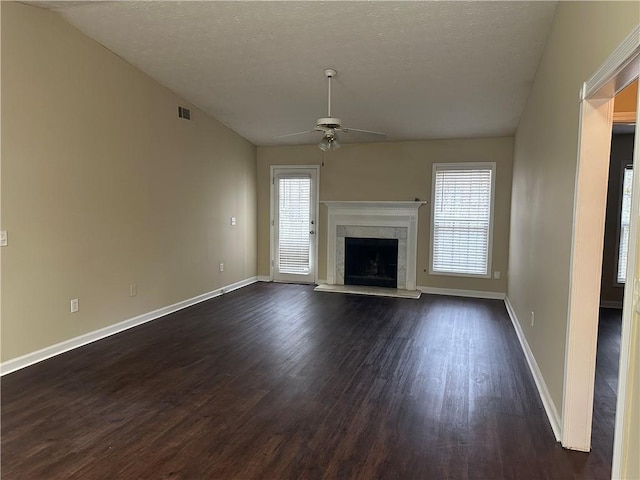 unfurnished living room with a textured ceiling, ceiling fan, a fireplace, and dark hardwood / wood-style floors