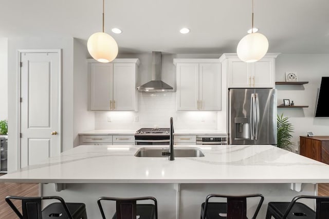 kitchen featuring pendant lighting, stainless steel appliances, white cabinetry, and wall chimney exhaust hood