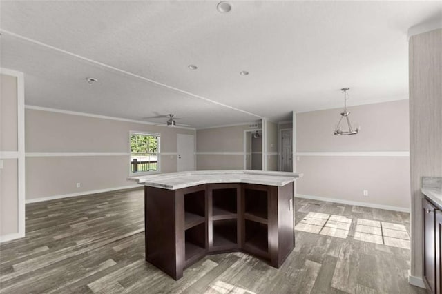 kitchen featuring dark brown cabinetry, ceiling fan, hanging light fixtures, dark wood-type flooring, and a kitchen island