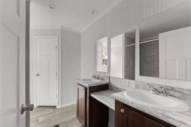 bathroom featuring walk in shower, vanity, wood-type flooring, and ornamental molding