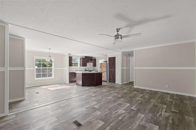 unfurnished living room featuring ceiling fan with notable chandelier, dark hardwood / wood-style floors, and crown molding