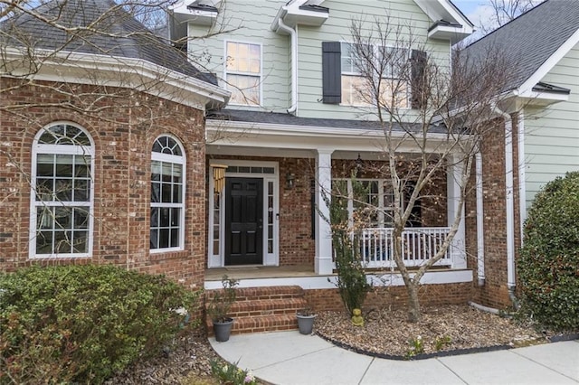 doorway to property with brick siding and a porch