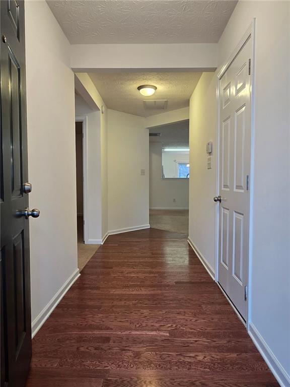 hall featuring a textured ceiling and dark hardwood / wood-style flooring