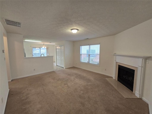 unfurnished living room with light carpet, a wealth of natural light, and a textured ceiling