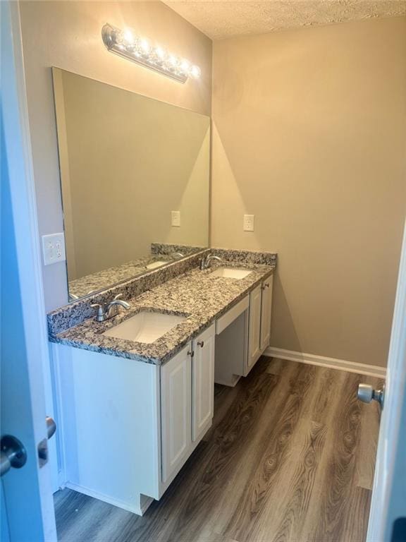 bathroom featuring hardwood / wood-style flooring, vanity, and a textured ceiling