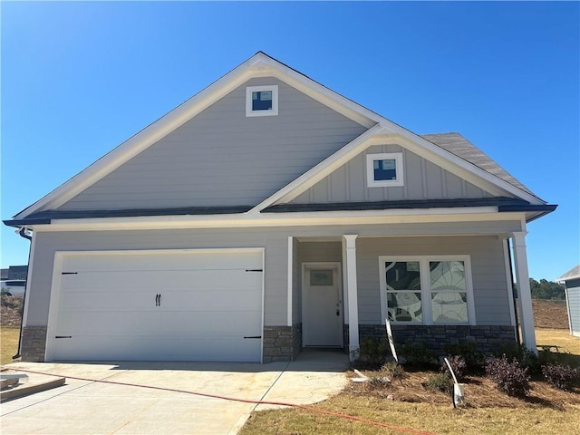 craftsman house featuring driveway, covered porch, board and batten siding, and stone siding