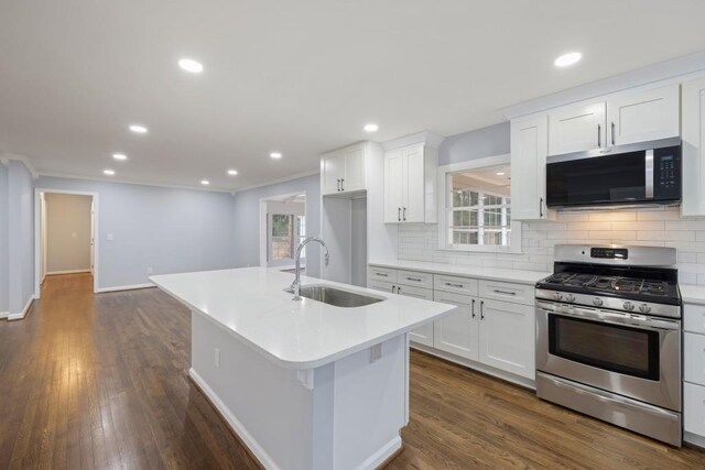 kitchen featuring appliances with stainless steel finishes, white cabinetry, lofted ceiling, sink, and an island with sink