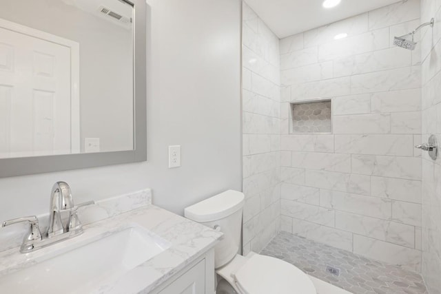 bathroom with vanity, toilet, and a tile shower