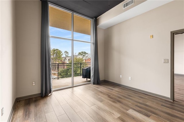 empty room featuring expansive windows and hardwood / wood-style floors