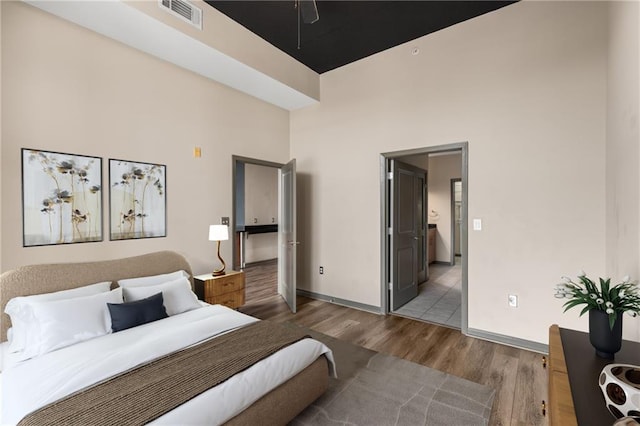 bedroom with light hardwood / wood-style floors and a high ceiling