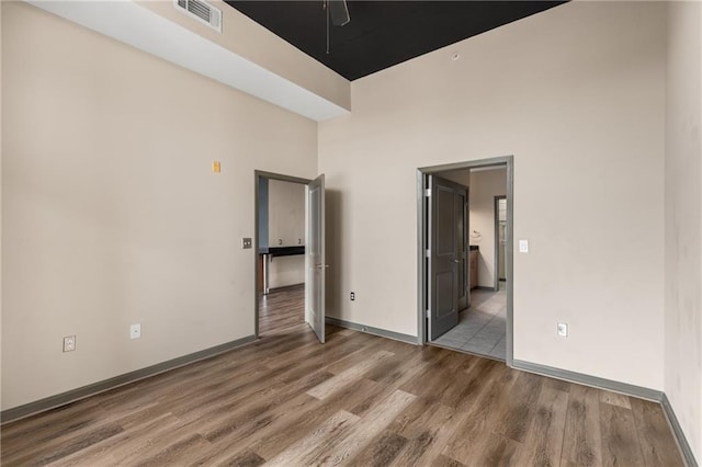 unfurnished bedroom with hardwood / wood-style flooring and a towering ceiling