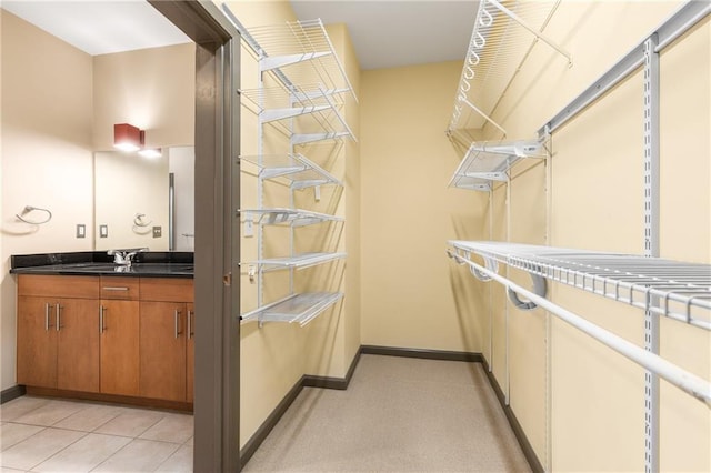 walk in closet with light tile patterned floors and sink