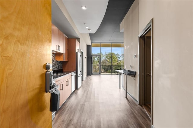 kitchen featuring tasteful backsplash, appliances with stainless steel finishes, a wall of windows, and light hardwood / wood-style floors