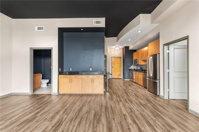 kitchen with tasteful backsplash, appliances with stainless steel finishes, light brown cabinetry, and light wood-type flooring