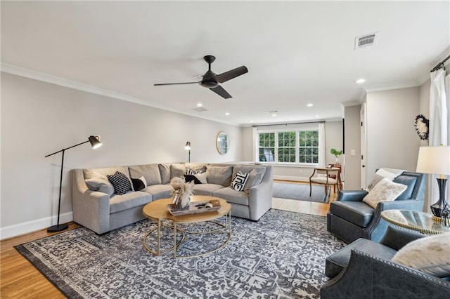 living room featuring visible vents, wood finished floors, baseboards, and ornamental molding