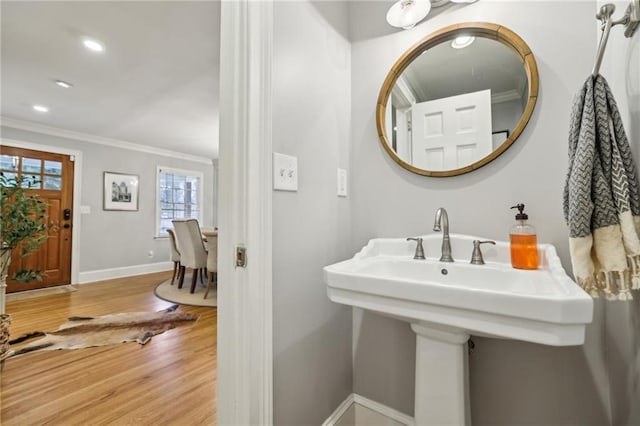 bathroom featuring wood finished floors, baseboards, recessed lighting, a sink, and ornamental molding