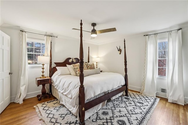 bedroom featuring ceiling fan, crown molding, baseboards, and wood finished floors