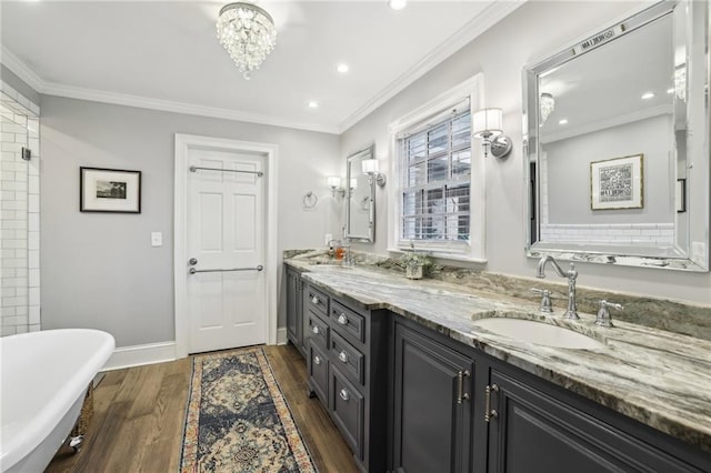 full bathroom featuring a freestanding bath, wood finished floors, crown molding, and a sink