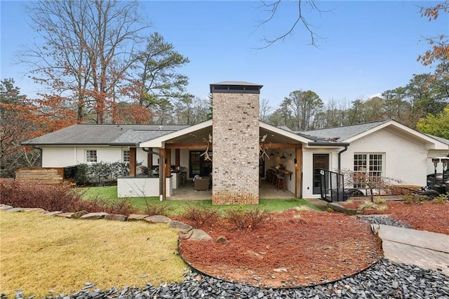 back of property with a patio, a lawn, and brick siding