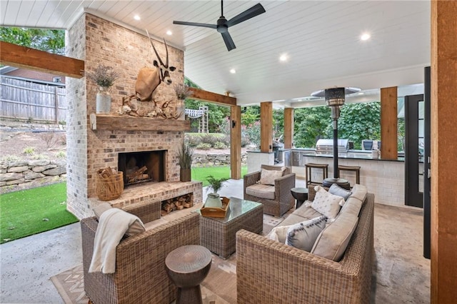 view of patio featuring fence, an outdoor living space with a fireplace, exterior kitchen, a grill, and a ceiling fan