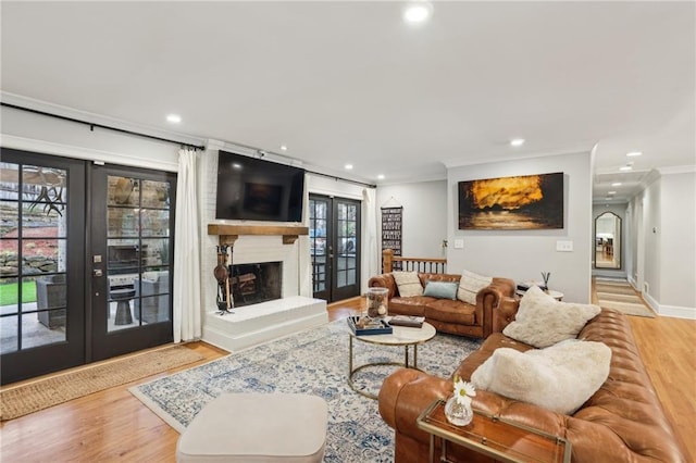 living room with wood finished floors, crown molding, recessed lighting, and french doors