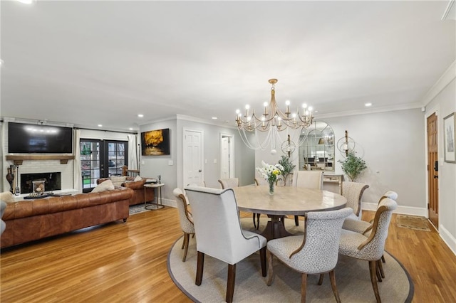 dining room with baseboards, light wood-style floors, ornamental molding, and a fireplace