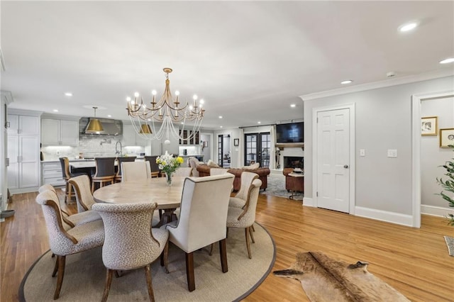 dining area with recessed lighting, a fireplace, light wood-style floors, and ornamental molding