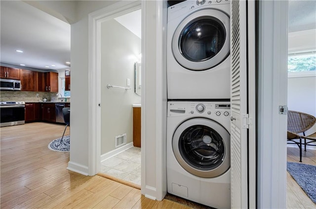 2985 Westbury Dr, Decatur, GA 30033 - clothes washing area featuring stacked washing machine and dryer, light wood finished floors, recessed lighting, and baseboards