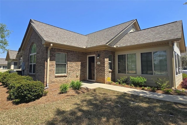 single story home with brick siding, roof with shingles, and a front yard