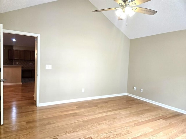 empty room featuring lofted ceiling, a ceiling fan, baseboards, and light wood finished floors