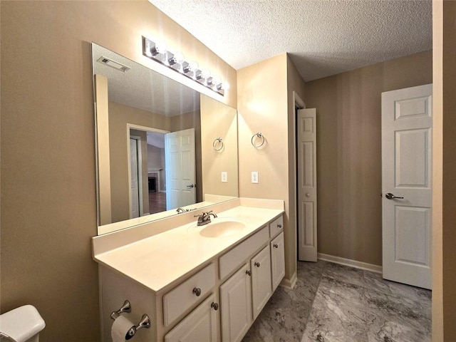 bathroom with marble finish floor, vanity, a textured ceiling, and visible vents