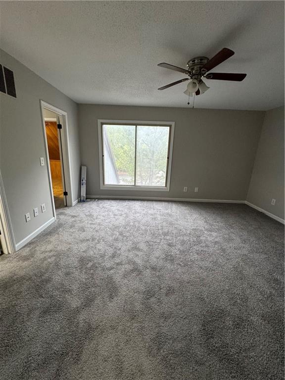 spare room featuring ceiling fan, carpet flooring, and a textured ceiling