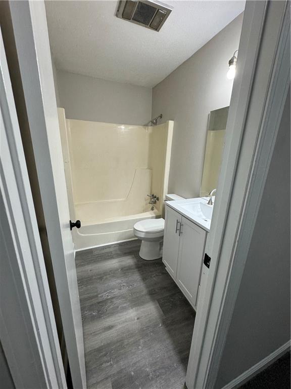 full bathroom with vanity, toilet, a textured ceiling, shower / tub combination, and hardwood / wood-style floors