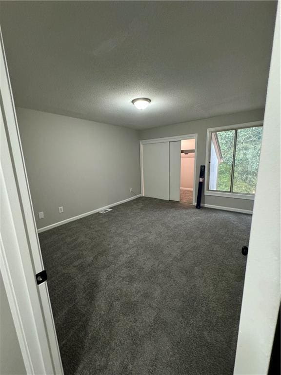 carpeted empty room featuring a textured ceiling