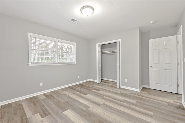 unfurnished bedroom with light wood-style floors, visible vents, a closet, and baseboards