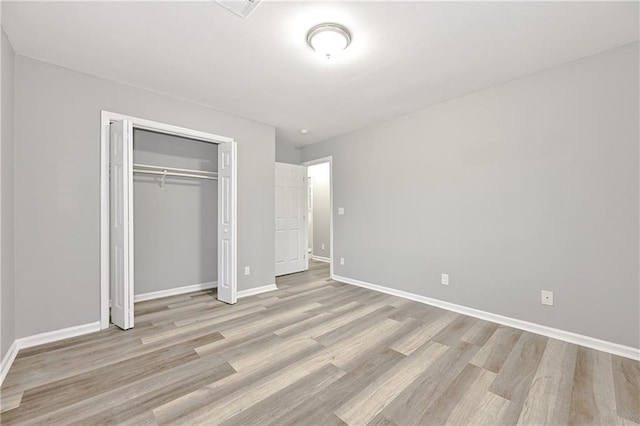 unfurnished bedroom with light wood-style floors, a closet, and baseboards