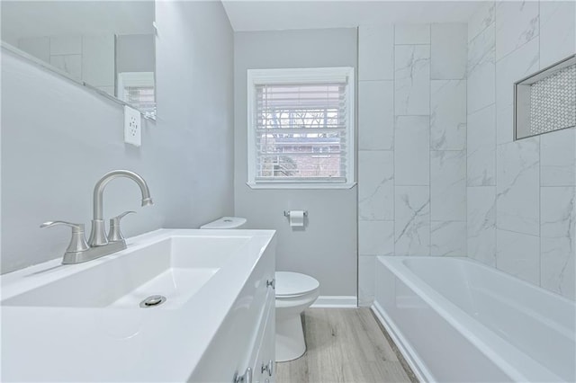 bathroom with toilet, vanity, baseboards, and wood finished floors