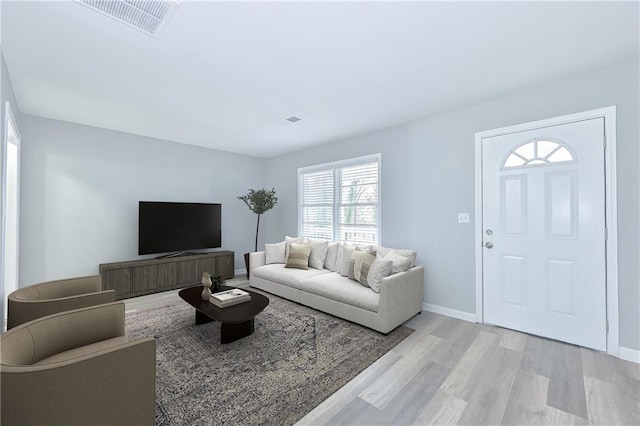 living room featuring visible vents, light wood-type flooring, and baseboards