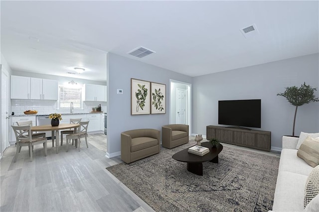 living room featuring light wood finished floors, visible vents, and baseboards