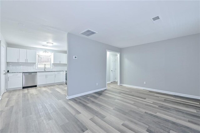 unfurnished living room with a sink, visible vents, baseboards, and light wood finished floors